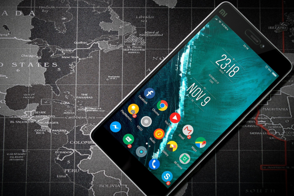 Black smartphone displaying a colorful app interface on a textured world map background.